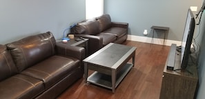 Living room 2 on first floor with 2 sofa sleepers and TV and half bath.