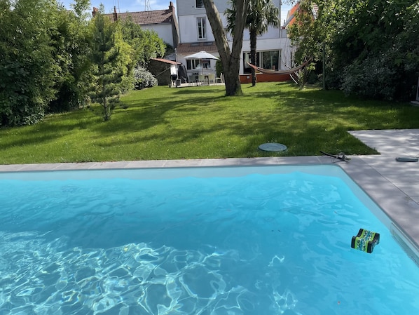 Piscine avec sur la gauche une terrasse exposée plein sud