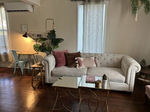 Warm and inviting living area with a plush sofa, stylish throw pillows, and a cozy corner desk perfect for work or relaxation.