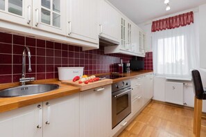 Fully equipped kitchen with red tile backsplash, white cabinetry, and wooden countertops.
