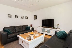 Open living area with a spacious layout featuring a black sofa, coffee table, and TV.
