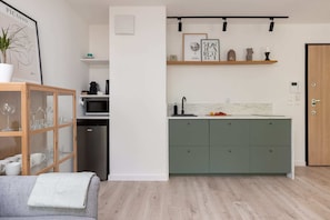 A modern kitchen with a simple design, featuring light green cabinetry and open shelving, giving it a clean and uncluttered appearance.