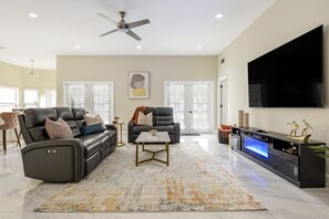 Welcome to the bright and airy living room, featuring an 85' TV & recliners.