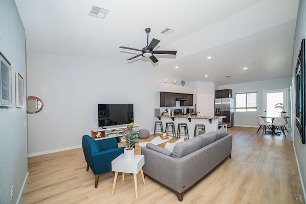 Inviting living room with open concept and 65" TV. Netflix & Disney+ included.