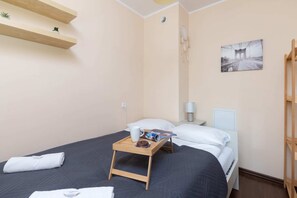 Bedroom with a double bed, soft blue bedding, and a functional bedside table.
