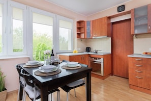 Kitchen and dining area with wooden cabinets, a dining table, and ample natural light.
