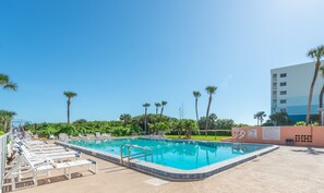 Sparkling heated pool surrounded by lush palm trees and open skies