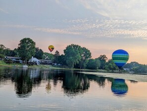 Hot air balloons flying over the lake. 