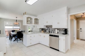 This kitchen and dining room is a modern and elegant space. It has stainless steel appliances, a fully stocked cabinet, and a dining table with chairs. You can enjoy your food in comfort and style here.