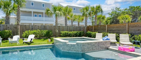 Lush backyard pool and hot tub area with loungers.