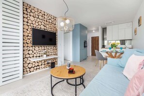 Another view of a modern living room with a blue sofa, round coffee table, and a TV mounted on a textured wall. The decor is elegant, with warm lighting adding to the ambiance.