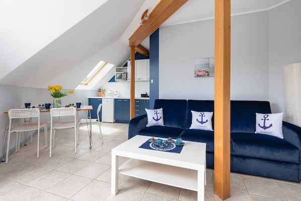 A cozy living area with a blue sofa, a white coffee table, and a nautical-inspired decor illuminated by natural light.