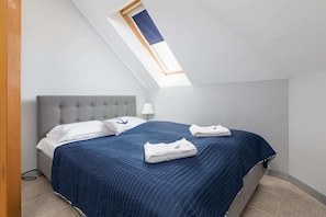 A comfortable bedroom corner with a double bed and slanted ceilings, offering a relaxing atmosphere.