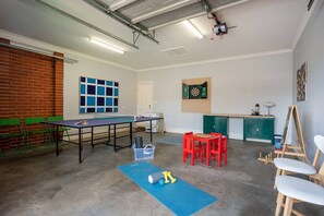 A garage has been converted into a functional games room with a ping pong table, darts, work out equipment, and kids' activities and can still fit one car for secure parking.