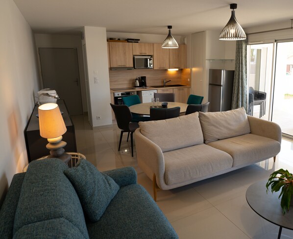 Large air-conditioned living room with dining table and open-plan kitchen. 