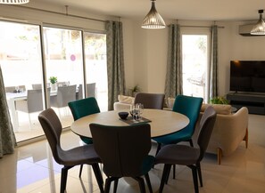 Large air-conditioned living room with dining table and open-plan kitchen. 