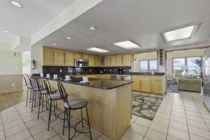 A massive kitchen features stainless steel appliances, 2 dishwashers, double wall ovens, a commercial ice maker, and an eat-at counter that seats 6 people.