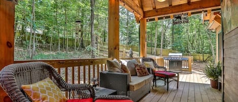 Outdoor seating with ceiling fan, 2 elevated dog beds and gas grill with walkway up to the fire pit.