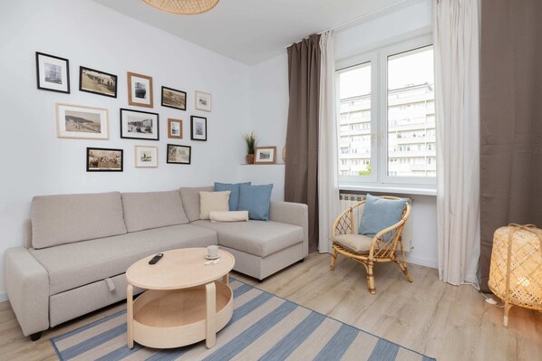 Cozy living room with a gray sofa, framed wall art, and a round wooden coffee table.
