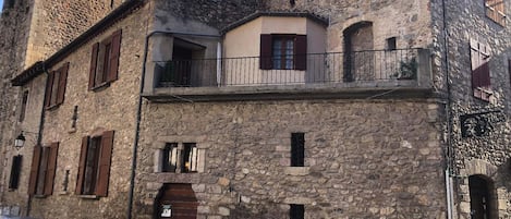 La maison saint Jacques, sa façade en pierre et sa terrasse.