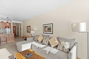 Cozy living area with mounted flat screen TV, gas fireplace, queen sleeper sofa, and balcony access.
