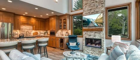 The show stopping living room boasts vaulted ceilings, striking stone fireplace, large flat-screen TV, stylish leather chair and ottoman, roomy sectional, coffee table, lots of natural light and close proximity to the stunning kitchen.
