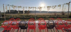 Ein großer Tisch im Garten auf der Terrasse mit Blick auf Wald und Wiese.