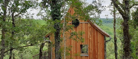 Cabane en bois nichée au milieu des arbres, chaleureuse et de tout confort.