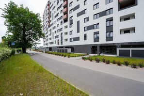 View of the building exterior with a walking path surrounded by greenery.
