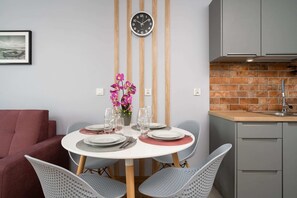 Dining area with a round table, elegant chairs, and a vase of fresh flowers.
