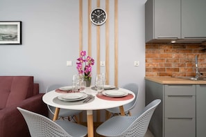 Dining area with a round table, elegant chairs, and a vase of fresh flowers.