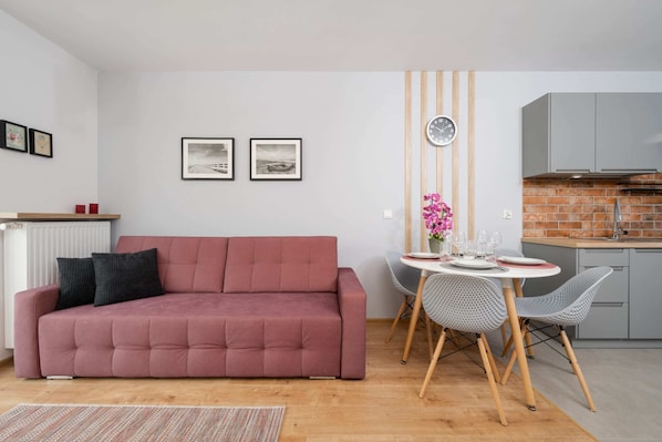 Bright and cozy living area with a pink sofa, dining table, and wall art accents.