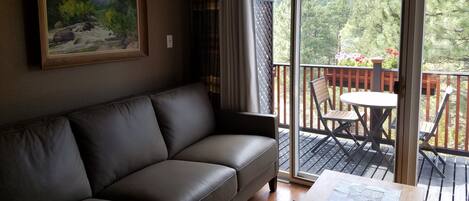 living room opens to deck with flower box, table and chairs, awning, and patio