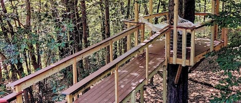 Breathtaking treehouse deck with hanging hammocks surrounded by woods