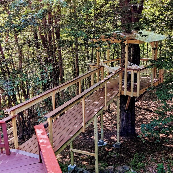 Breathtaking treehouse deck with hanging hammocks surrounded by woods