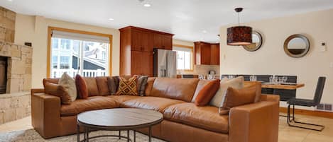 Brown leather sectional couch in the living room with circular modern wooden coffee table