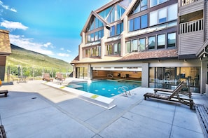 Outdoor pool deck with wooden poolside lounge chairs overlooking the mountain