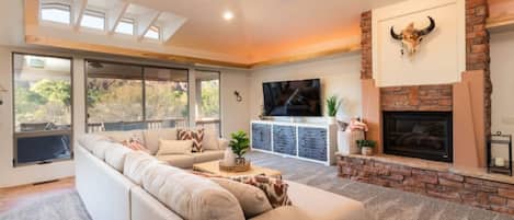 Main living area w/ stunning views of Sedona, a 75" smart TV and gas fire place