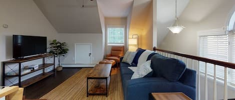 Living room space wide open to kitchen for relaxation and socialization.  Coffee table transforms into a laptop work station on its handy hinges.  The relaxing couch doubles as a Queen size pull out by night.