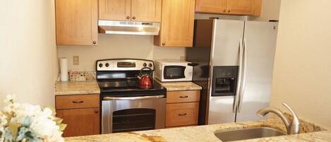 Kitchen w/ granite countertops and stainless steal appliances.