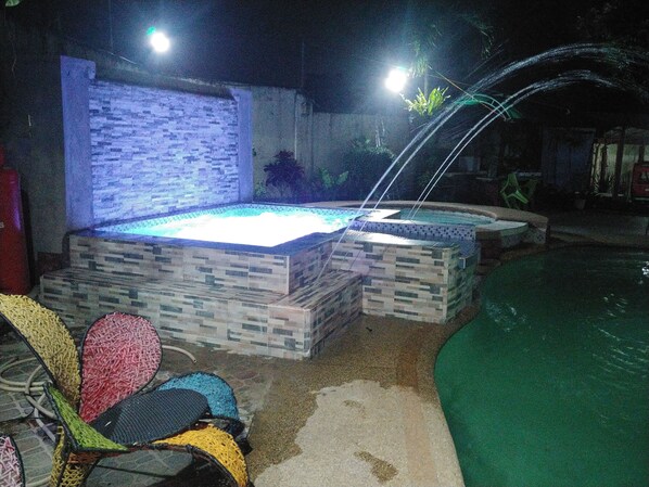 Hot tub at night with jetsi into the swimming pool.