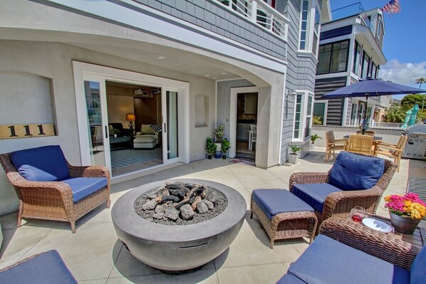 This is the downstairs unit. The patio has a fire feature, a loveseat, chairs, and end tables. On the other side of the patio, you have a dining table BBQ, and a hose to rinse off the sand. The picture shows the area that is included with the unit.