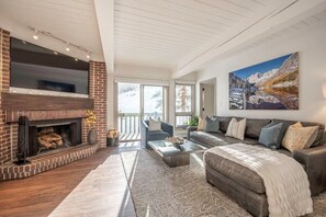 Spacious living room with wood burning fireplace and view of ski hill