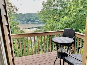 View of Lake Lure and surrounding mountains along with large upstairs balcony from the dining table. Upstairs balcony includes 4 high top chairs and two high top tables for enjoying coffee, cocktails, or a meal while looking at paradise.