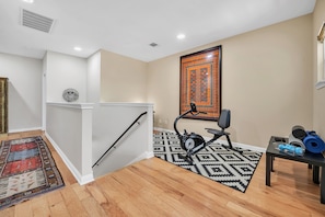 Office area with exercise bike, weights, table and chair for work at home.  
