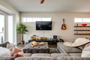 Living room area with large sectional, plush cushions, and a 65" TV