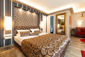 Großes Schlafzimmer mit modernem Hotel-Boxspringbett und angrenzendem Bad