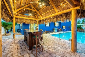 Tiki bar with ceiling fans and night lighting.