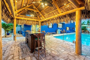 Tiki bar with ceiling fans and night lighting.