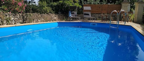 La piscine privative au logement et sa terrasse bois (transats, table, chaises)